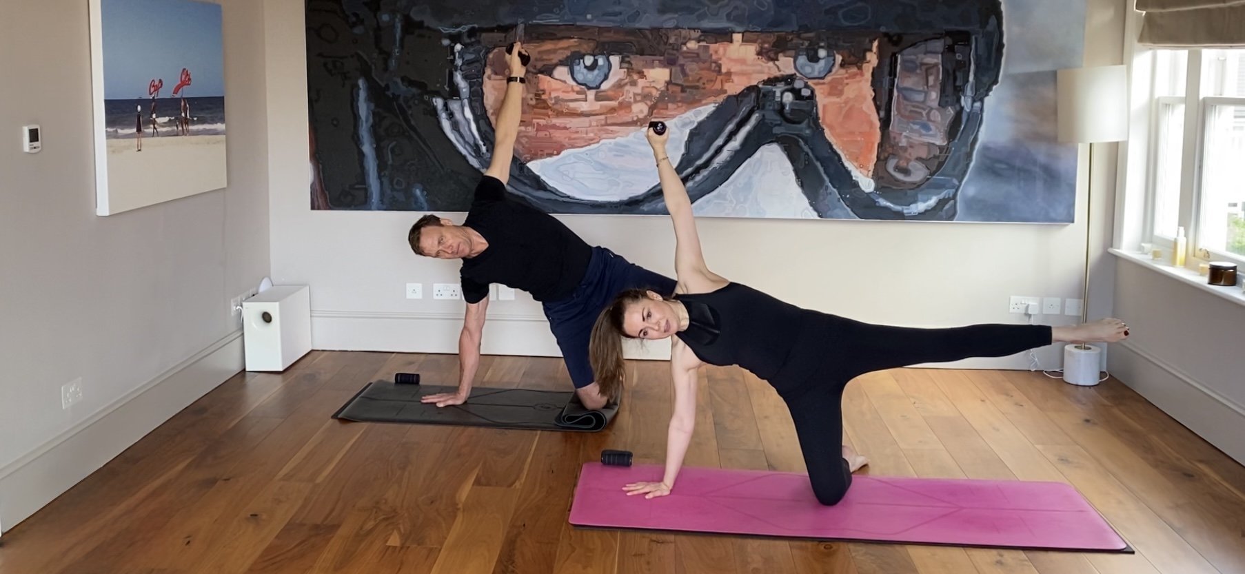 Two clients holding a side plank with weights in the Wimbledon Village studio